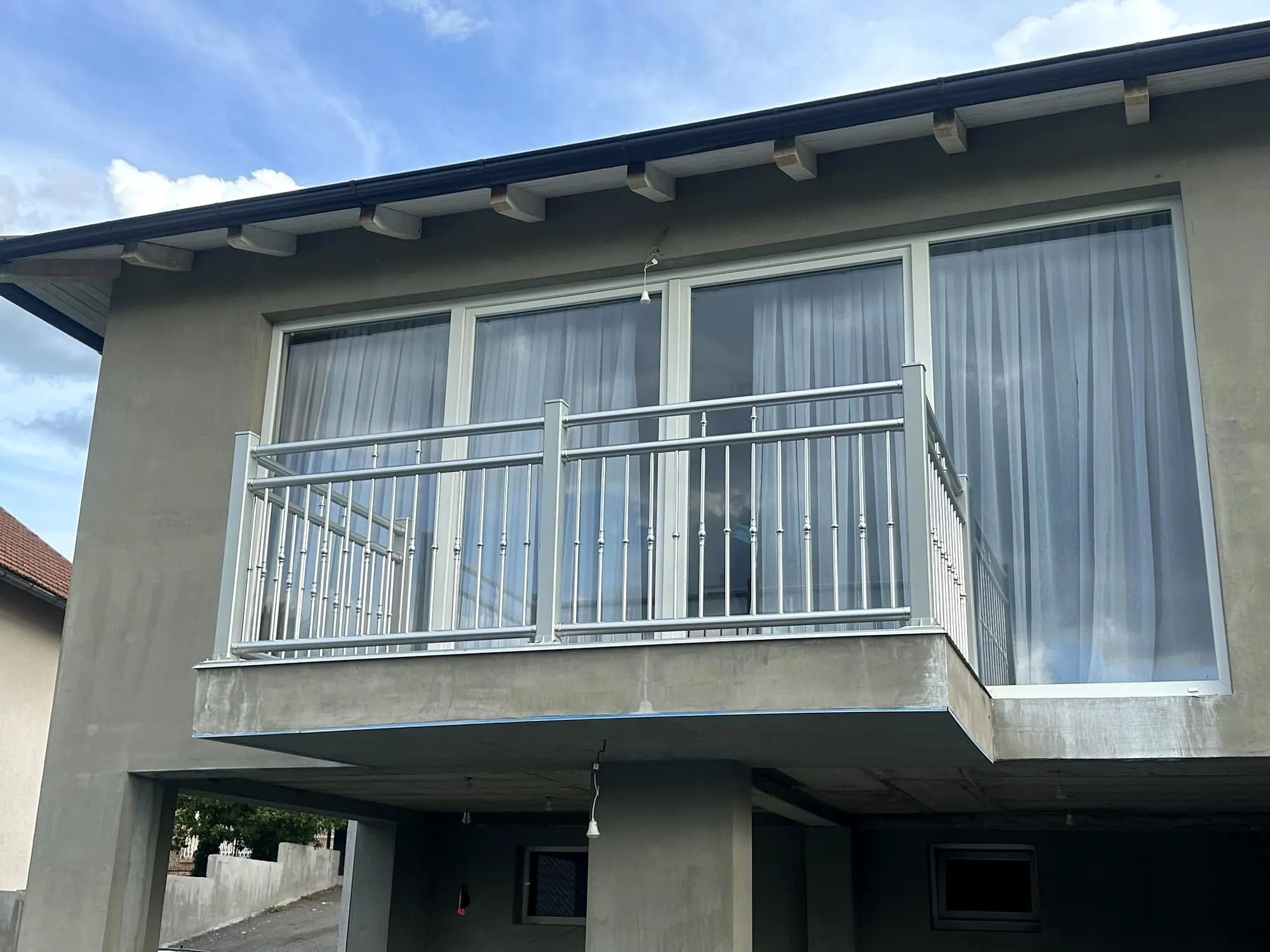 Weißes Aluminiumgeländer als französischer Balkon vor großen Fenstern