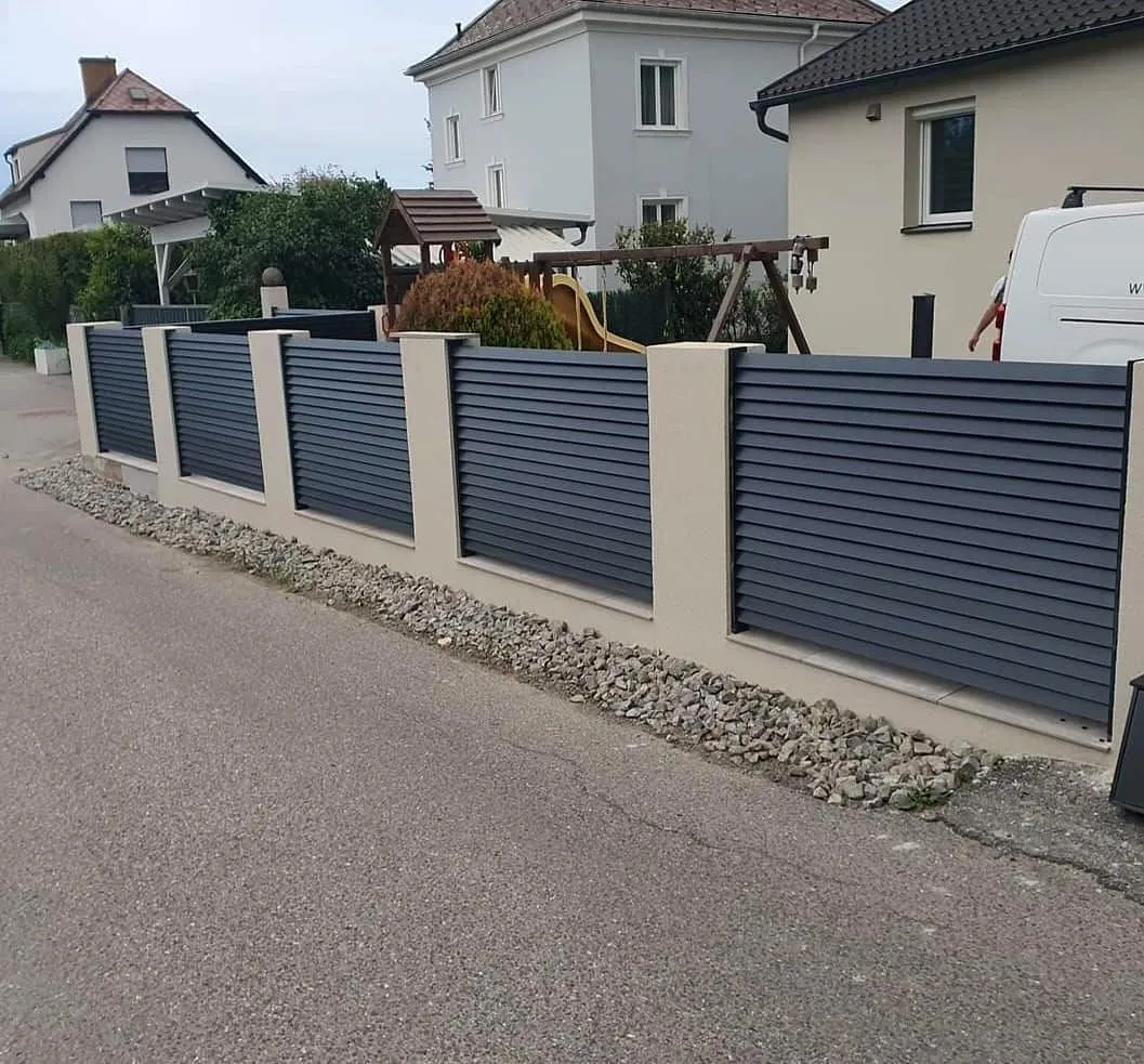 Lamellenzaun aus Aluminium zwischen gemauerten Säulen